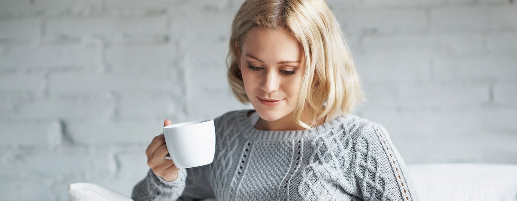 Person sitting on a couch drinking coffee