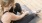 woman in workout gear, sits on a yoga mat and ties her shoe